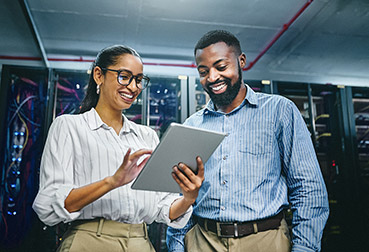 Pair of IT professionals working on a tablet in a server room