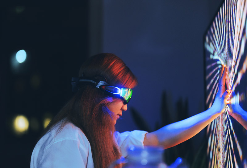 Young woman wearing augmented reality glasses touching screen with hands